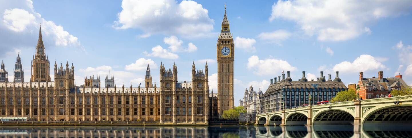 ביג בן ובית הפרלמנט בלונדון אנגליה, עם גשר וסטמינסטר מעל נהר התמזה, תחת שמיים כחולים עם עננים לבנים