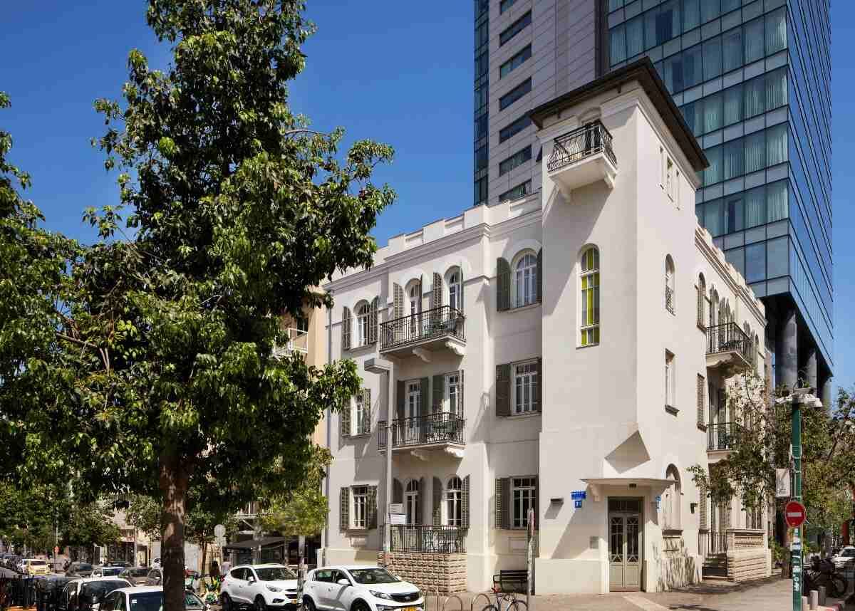 בניין בכר האוס בתל אביב לצד מגדל מודרני מזכוכית ברקע