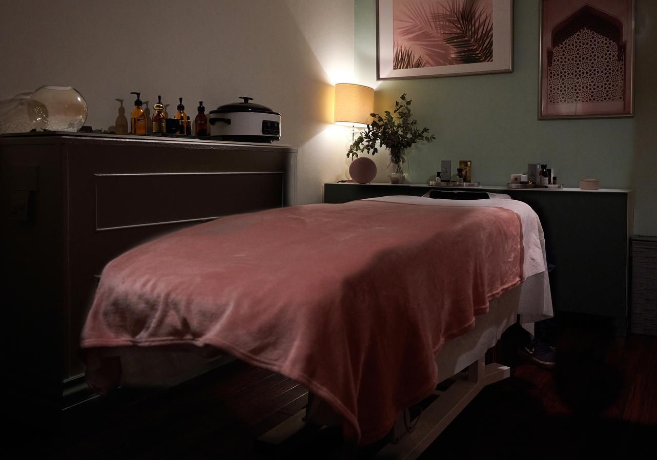 חדר טיפולים מעוצב במלון לאונרדו The Dilly לונדון עם מיטת טיפולים מכוסה בשמיכה ורודה