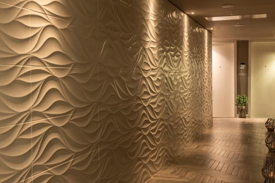 מסדרון מעוצב בסגנון יוקרתי במלון הרודס הרצליה, עם קירות בתבליט גלים ותאורה רכה