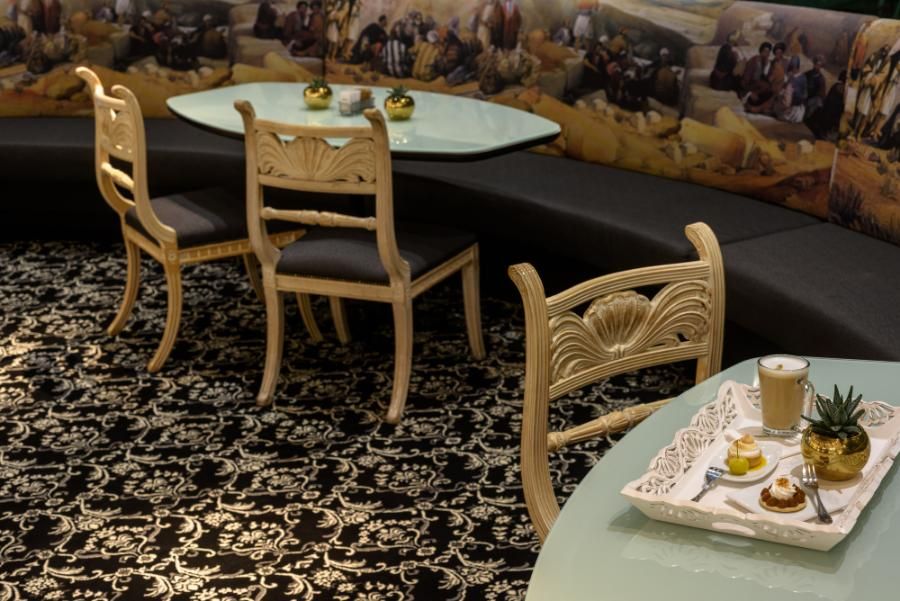 פינת ישיבה יוקרתית עם שולחנות זכוכית, כיסאות מעוצבים ומגש קפה עם קינוחים מפנקים