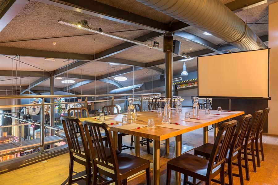 חדר ישיבות אינטימי במלון לאונרדו אלמרה סנטר, עם שולחן עץ בהיר מסביבו כיסאות ומסך למקרן 