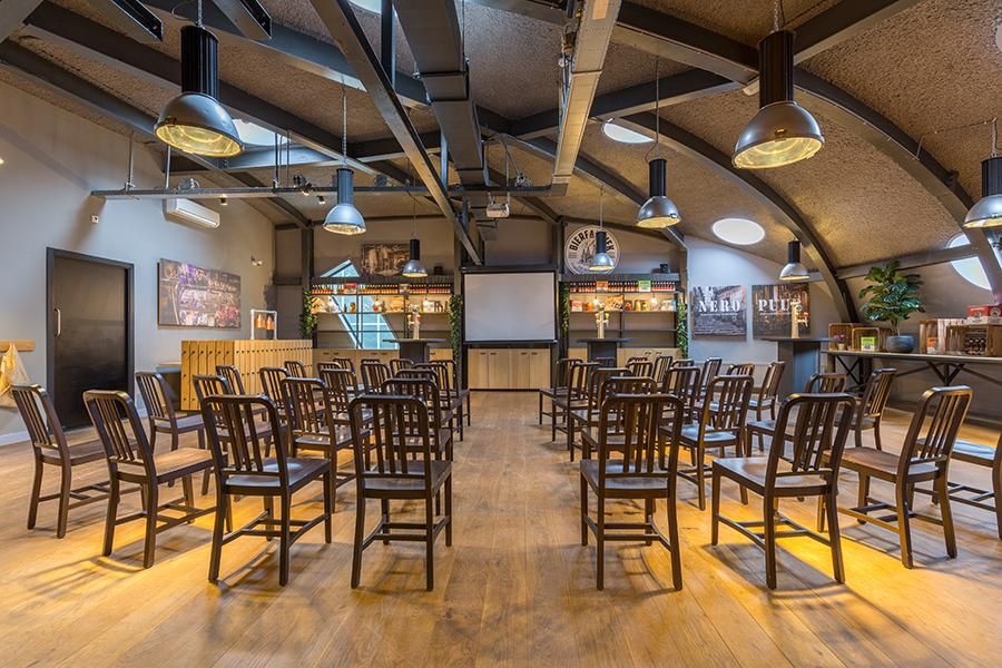 אולם כנסים במלון לאונרדו אלמרה סנטר, עם תקרה גבוהה, תאורה תעשייתית וסידור מושבים להרצאות ואירועים