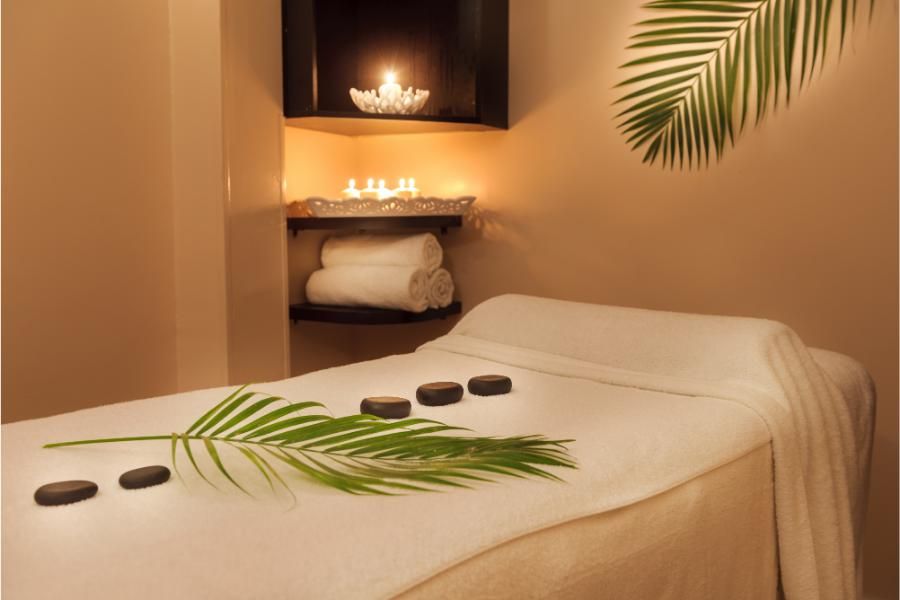 חדר טיפולי  באווירת שלווה עם נרות ואבנים מונחוץ בשורה על מיטת טיפול 