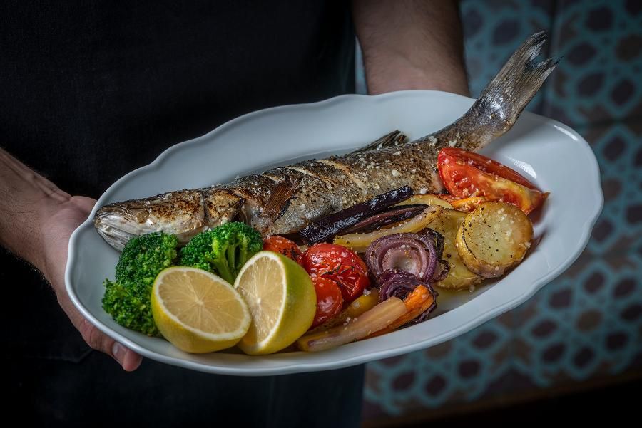 דג שלם אפוי בתנור מוגש עם ירקות צלויים ולימון