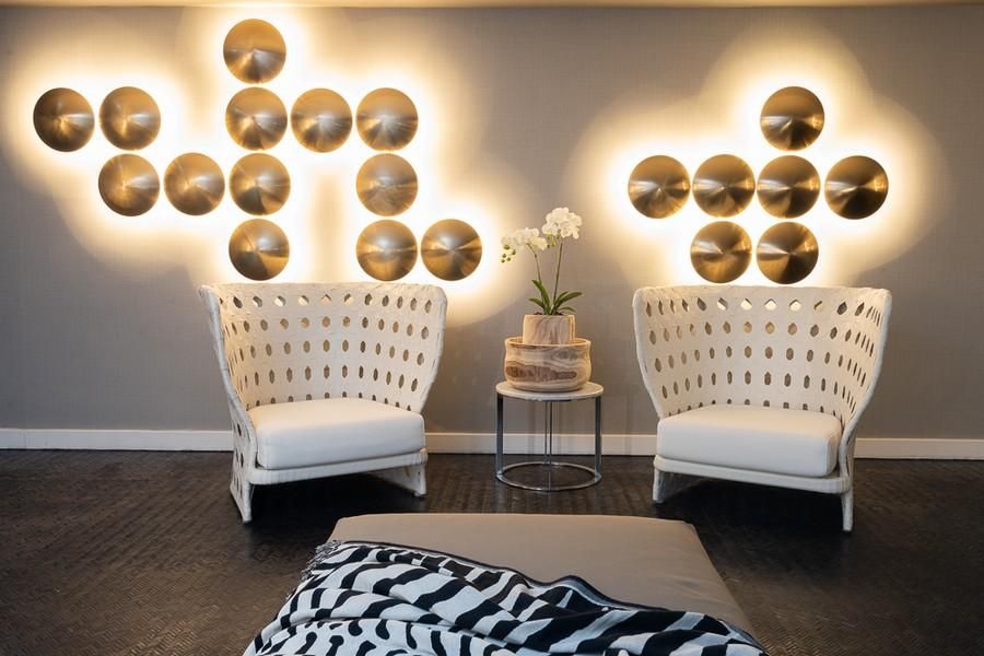 שתי כורסאות עם חורים עגולים בגב, מול קיר עם תאורה בצורת עיגולים  וביניהן שולחן קטן עם סידור פרחים 