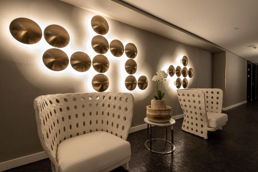 פינת ישיבה בספא מלון NYX הרצליה עם כורסאות לבנות, שולחן וסחלב, ותאורה דקורטיבית על הקיר