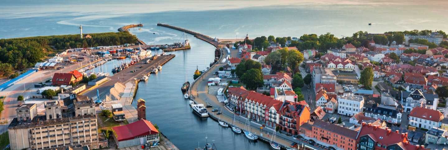 עיירת נמל בפולין עם מרינה, נהר מתפתל, מבנים היסטוריים וגגות אדומי