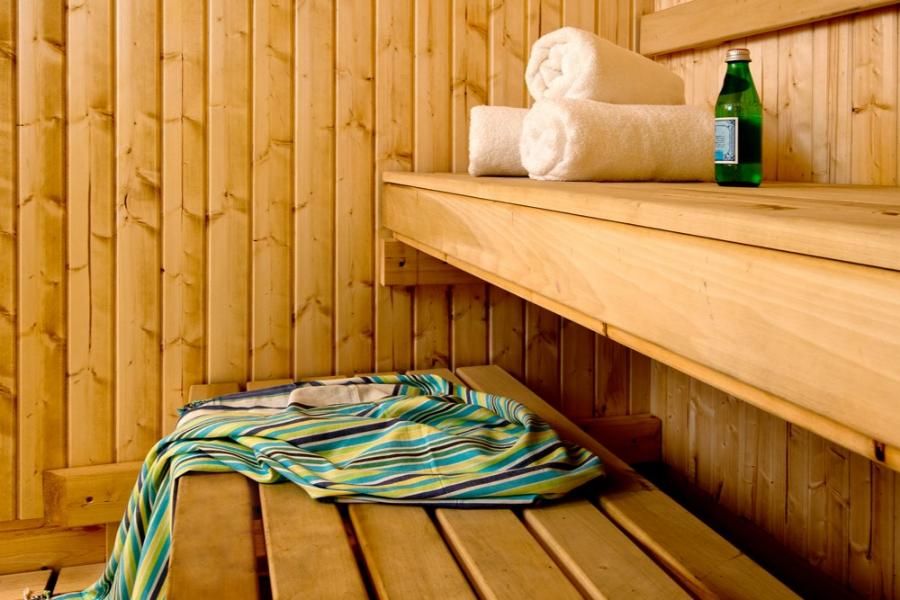 סאונה מעוצבת בעץ טבעי במלון לאונרדו ירושלים עם מגבות מסודרות ובקבוק מים