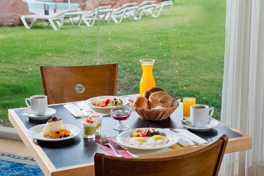 ארוחת בוקר במלון לאונרדו פלאזה אילת עם מאפים, ביצים, קפה ומיץ תפוזים, מול נוף ירוק