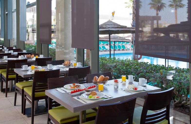 שולחנות ערוכים עם ארוחת בוקר לצד חלון עם נוף לבריכה 