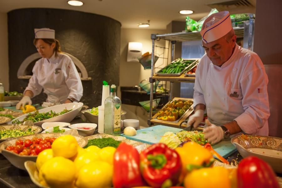 שפים במטבח חותכים ירקות טריים וצבעוניים