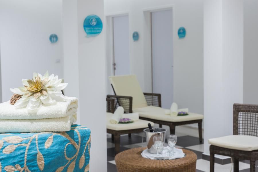 פינת המתנה מפנקת בספא יו קורל ביץ' קלאב אילת עם מגבות, כוסות יין וכורסאות